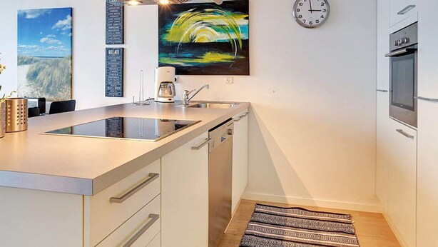 A modern kitchen with a central island, a coffee machine, a clock, and a painting on the wall. - 8 Person Holiday Home in Hadsund-by Traum (Hadsund)