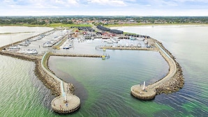 A marina with boats docked, a pier, and a circular island with a lighthouse. - 8 Person Holiday Home in Hadsund-by Traum (Hadsund)