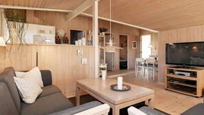 En hyggelig stue med en sofa, et spisebord og et fjernsyn.