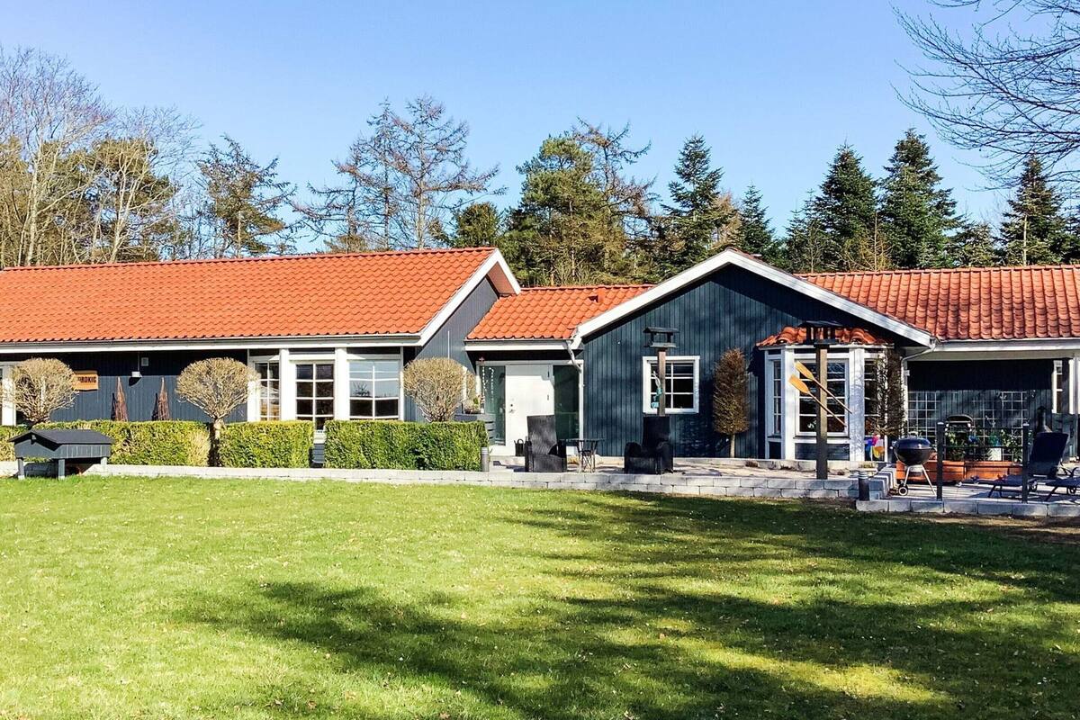 A two-story building with a red-tiled roof, a covered porch, and a well-maintained lawn.