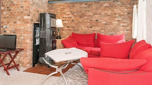 A cozy room with a brick wall, a red sofa, a glass table, and a vintage radio. - 4 Person Holiday Home in Hojer-by Traum (Højer)