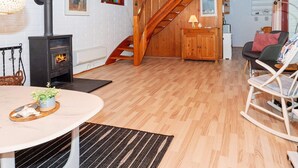 Un salon chaleureux avec un escalier en bois, une cheminée et un coin repas comprenant une table et des chaises.