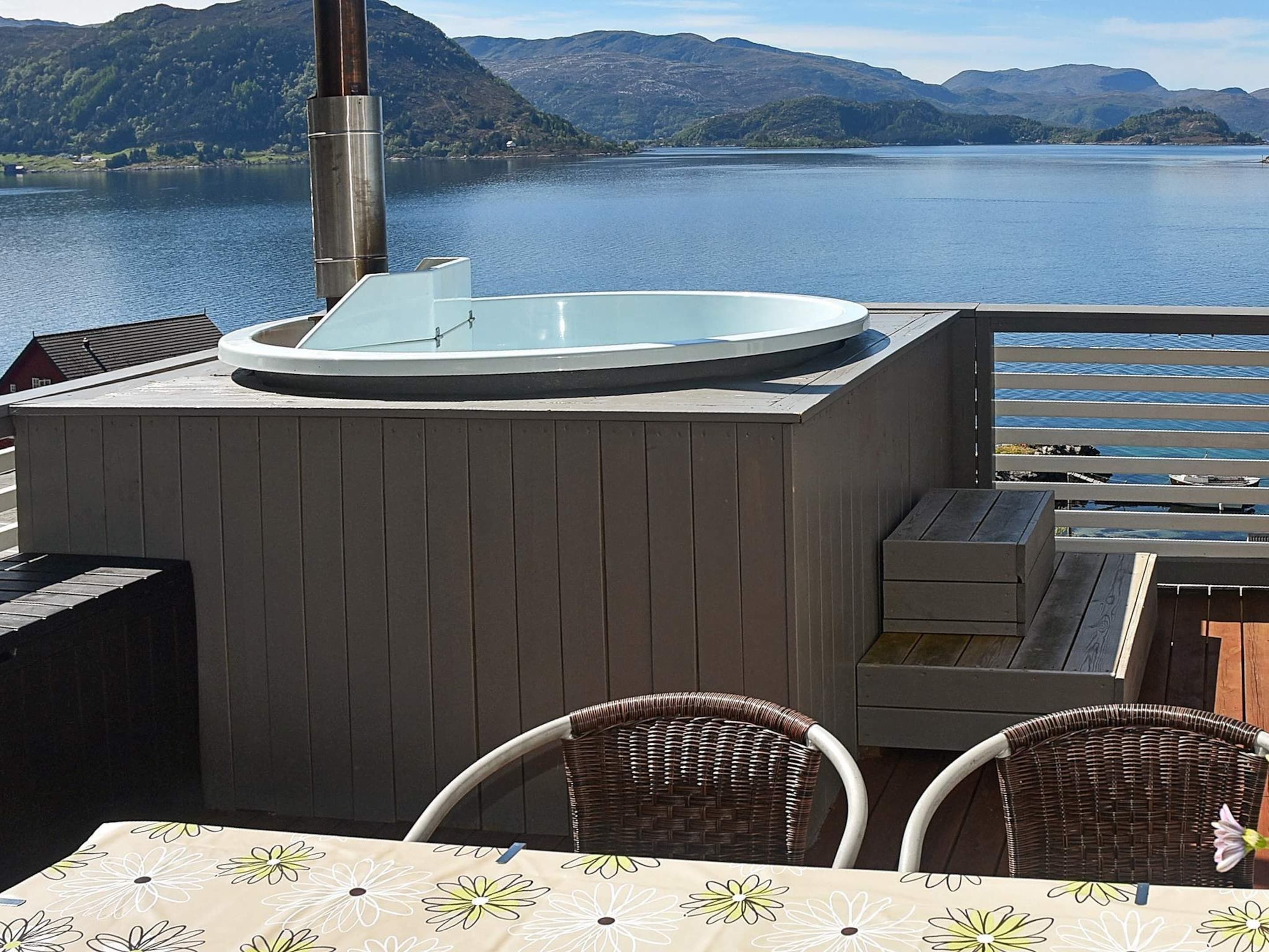 Een hottub op een terras met uitzicht op een meer en bergen.