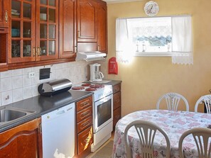 A kitchen with wooden cabinets, a dishwasher, a stove, and a dining area with a table and chairs.