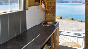 Een keuken met uitzicht op een meer, een gootsteen en een slang.