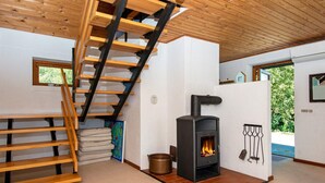 A modern interior with a wooden staircase, a built-in wood stove, and a view of the outdoors.