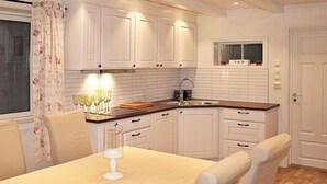 Eine moderne Küche mit weißen Schränken, einer Holztischplatte und einem Essbereich mit Tisch und Stühlen.