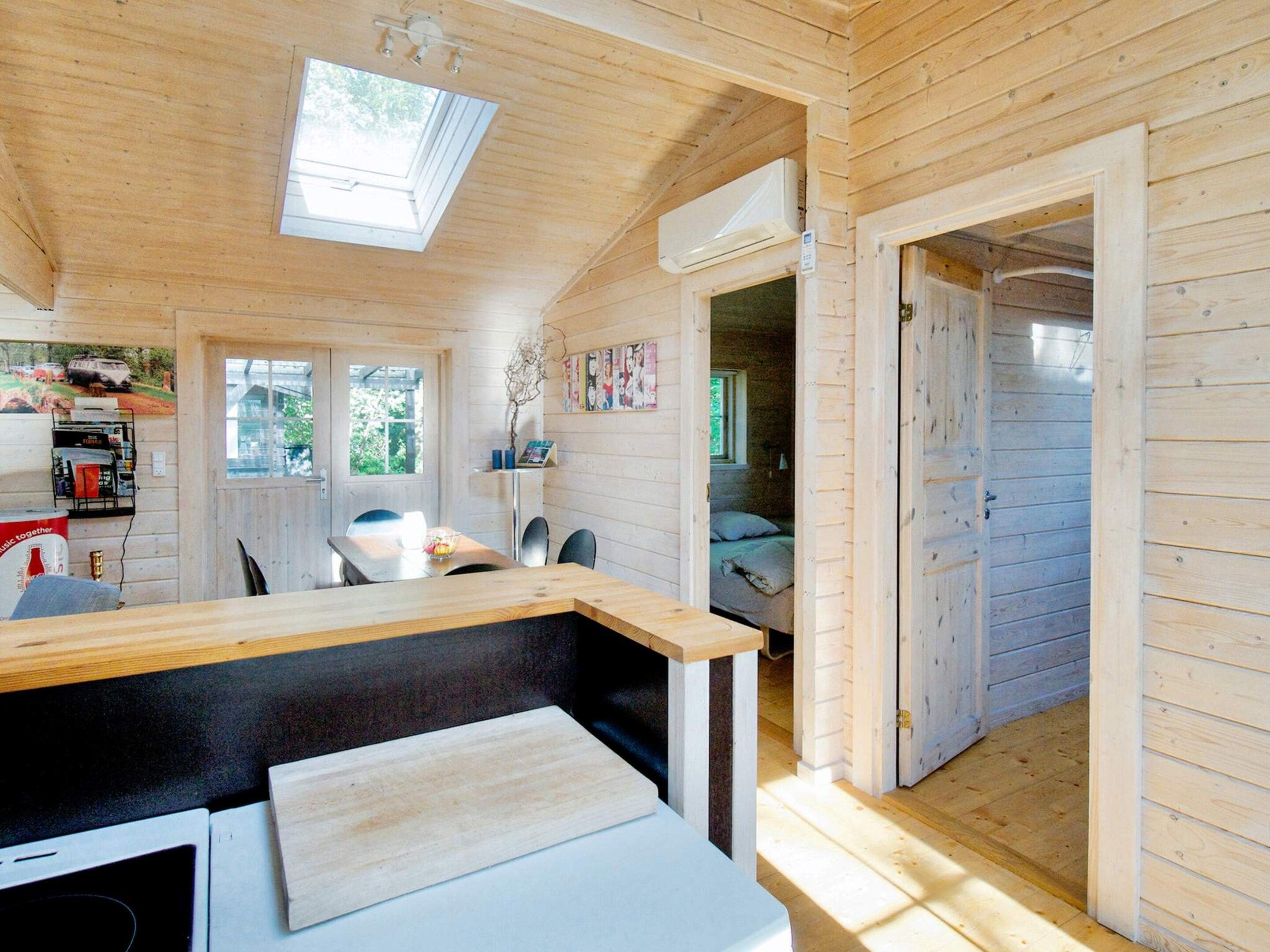 A wooden cabin with a dining area, a bed, and a kitchen area.