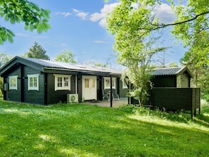 A cabin with a front porch, a small attached shed, and a grassy yard.