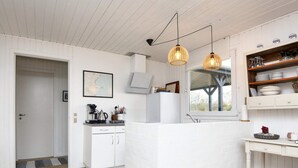 Une cuisine moderne avec des meubles blancs, un îlot central intégré et des luminaires suspendus.