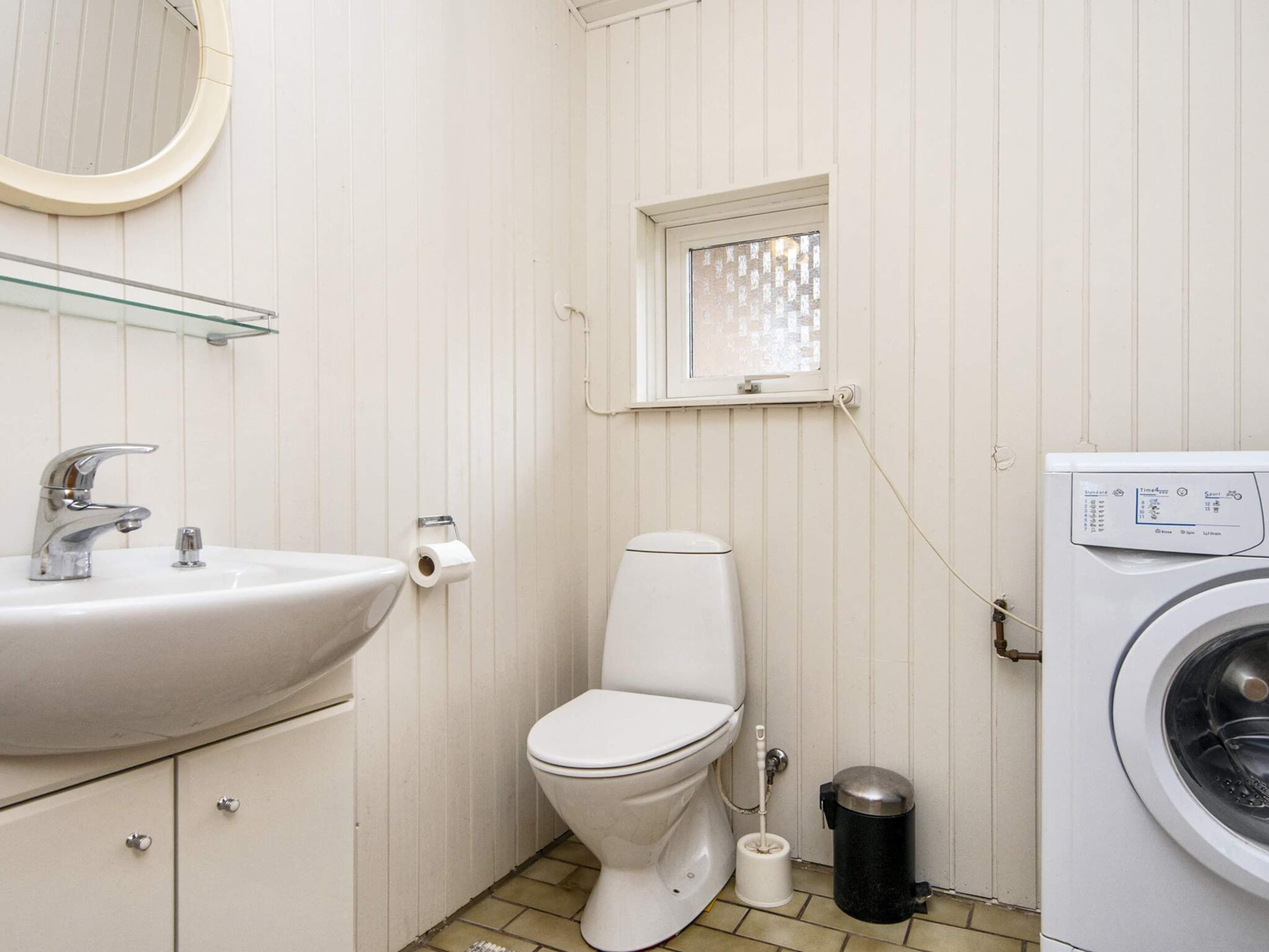 A small, compact bathroom with a sink, toilet, and washing machine.
