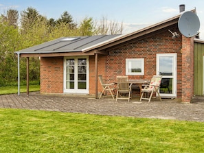 A brick house with a patio, a table with chairs, and a satellite dish. - Vintage Holiday Home in Struer near Open Field (Struer)