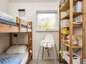 A bunk bed room with a white chair, a window, and wooden shelves with books and toys. - Vintage Holiday Home in Struer near Open Field (Struer)