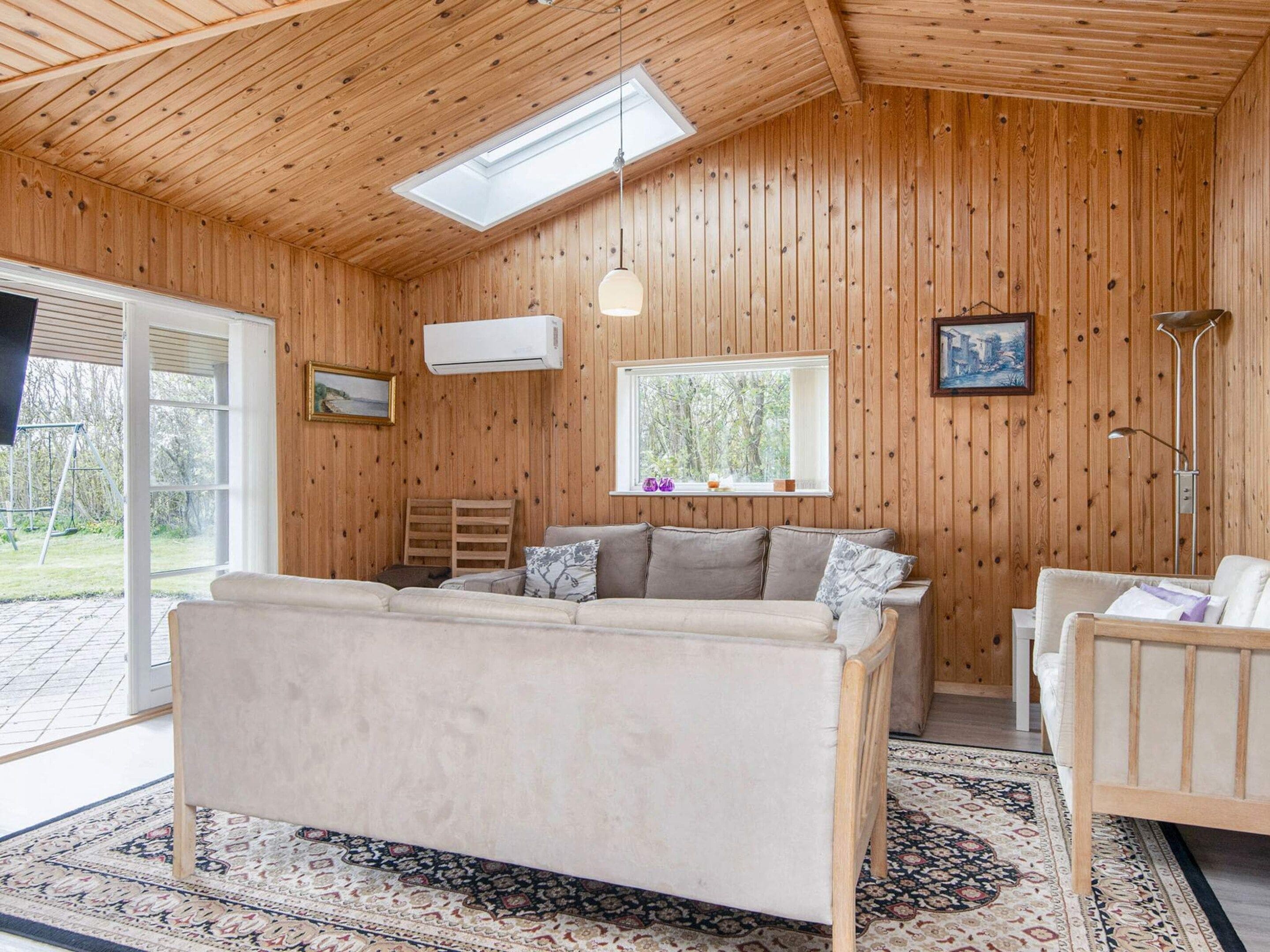 Ein Zimmer mit Holzwänden, einer Couch, einem Fenster und einem Dachfenster.