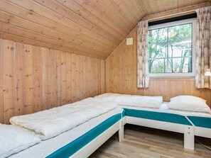 A room with wooden walls and a window with curtains. There are two beds with white bedding and teal bedspreads. - 4 Star Holiday Home in Oksbol (Oksbol)