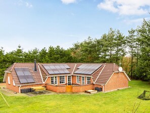 A two-story brick house with a sloped roof, solar panels, and a chimney. - 4 Star Holiday Home in Oksbol (Oksbol)