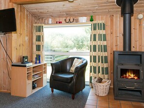 A cozy room with a fireplace, a leather chair, a television, and a bookshelf. - 6 Person Holiday Home in Fano (Fano)