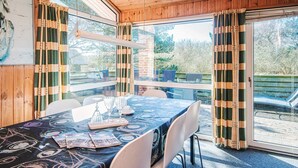 A wooden cabin with a dining table set for two, a large window, and a view of the outdoors. - 6 Person Holiday Home in Fano (Fano)