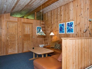 A wooden interior with a sofa, a table, and a lamp.