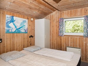 A wooden-paneled room with a bed, a window with curtains, a painting on the wall, and a white wardrobe. - 6 Person Holiday Home in Fano (Fano)