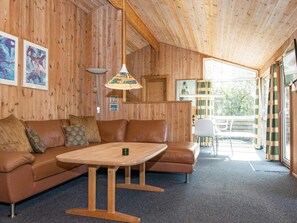 A wooden interior with a sofa, a table, and a chair.