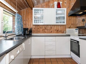 Keittiössä on valkoiset kaapit, mikroaaltouuni, uuni ja kahvinkeitin.