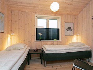 A room with two beds, a small table, a window with blinds, a hanging light fixture, and a framed picture on the wall. - 5 Star Holiday Home in Ulfborg (Ulfborg)