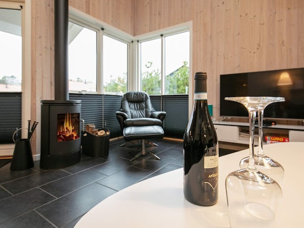 A modern living room with a fireplace, a leather chair, a wine bottle, and a glass.