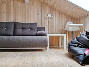 A room with a sofa, a small table, a lamp, and a bean bag chair. - 5 Star Holiday Home in Ulfborg (Ulfborg)