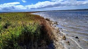 Un paisaje costero con cielo despejado, una masa de agua y una zona cubierta de hierba.