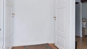 Un couloir avec des portes blanches, un plancher en bois et un tapis.