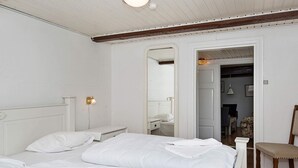 Une chambre à coucher avec un grand lit, une table de chevet, une chaise et un miroir.