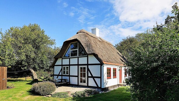 A traditional half-timbered house with a thatched roof, surrounded by lush greenery. - 5 Person Holiday Home in Humble (Sydlangeland)