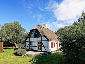 A traditional half-timbered house with a thatched roof, surrounded by lush greenery. - 5 Person Holiday Home in Humble (Sydlangeland)