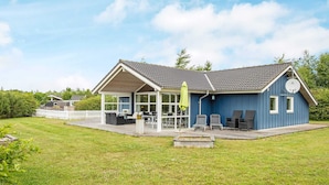 A blue house with a covered patio, a lawn, and a small deck. - 4 Star Holiday Home in Hemmet (Hemmet)