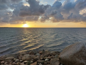 Ein Sonnenuntergang über dem Meer mit einer felsigen Küstenlinie.