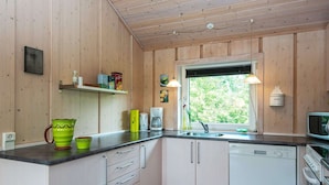 A kitchen with wooden walls, a window, a sink, a coffee maker, and a dishwasher. - 4 Star Holiday Home in Hemmet (Hemmet)