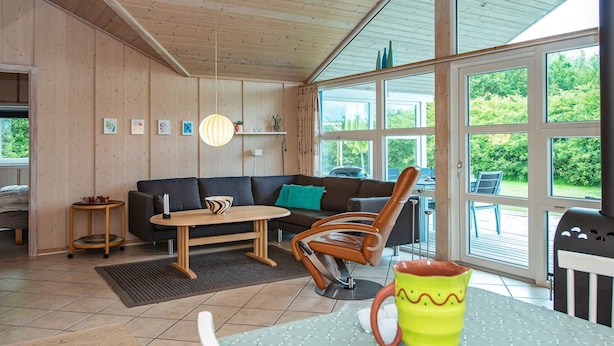 A cozy living room with a wooden ceiling, a sofa, a coffee table, and a dining table. - 4 Star Holiday Home in Hemmet (Hemmet)