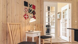 A wooden-paneled room with a desk, two chairs, a lamp, and a door leading to a kitchen area. - 4 Star Holiday Home in Idestrup (Idestrup)