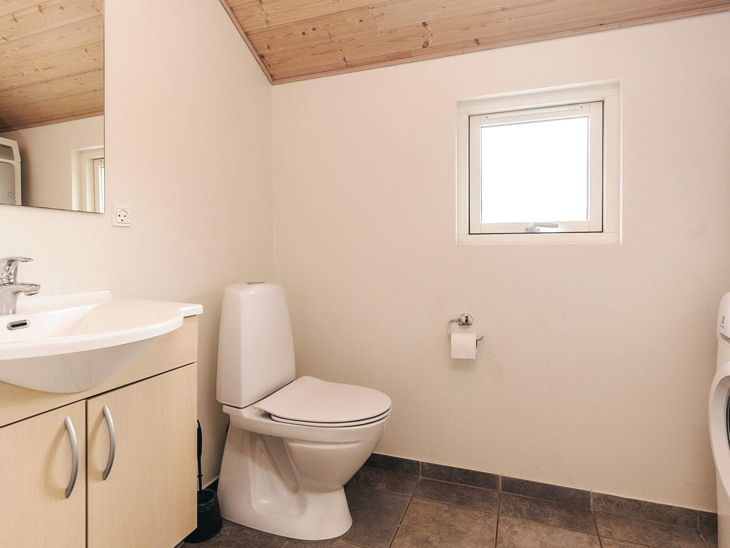 Un baño con inodoro, lavamanos y ventana.