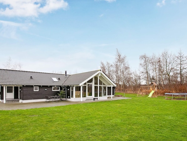 A house with a large patio, a covered outdoor area, and a playground with a slide.