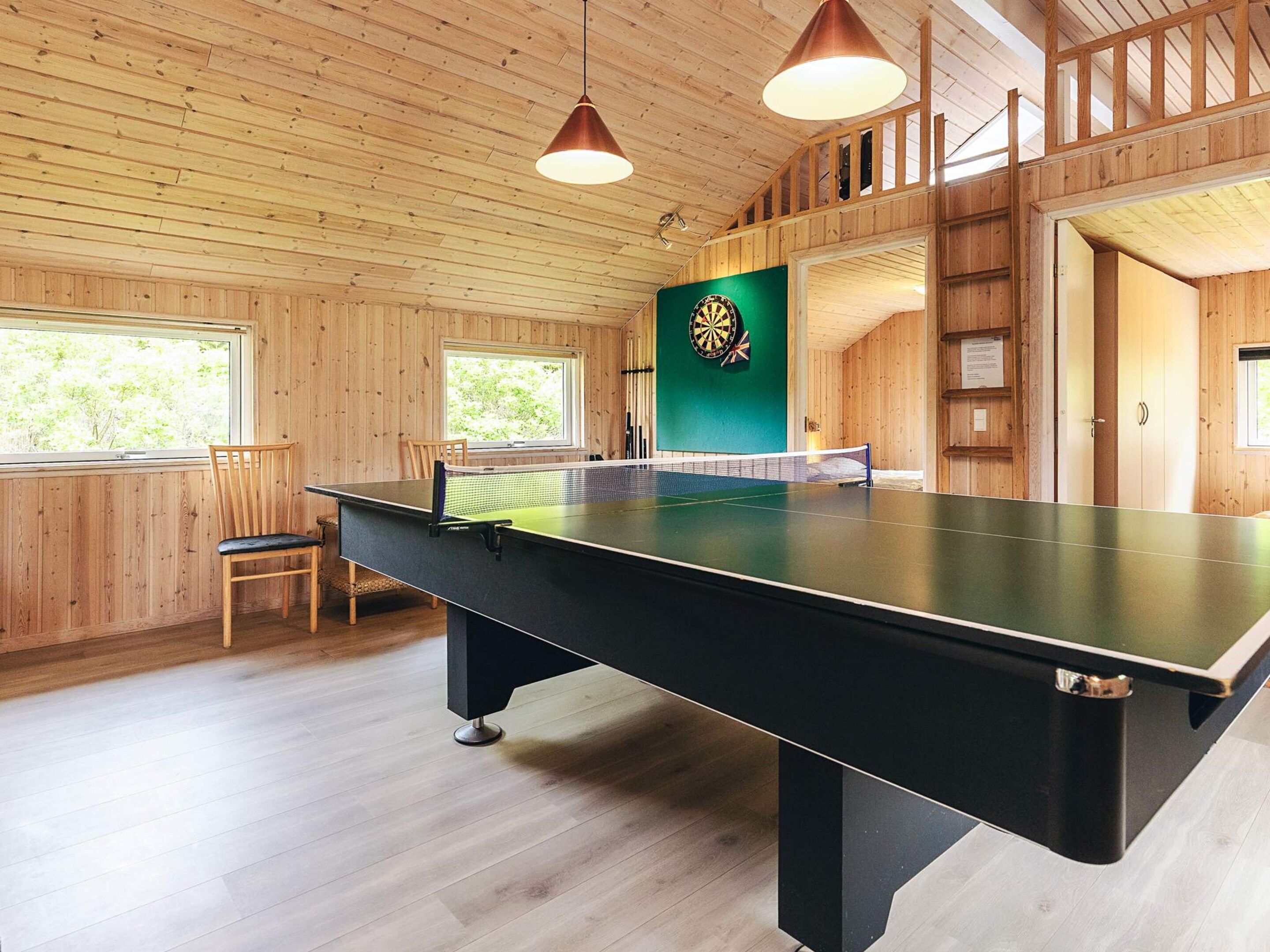 Un tavolo da ping pong in una stanza con pareti in legno e un bersaglio da freccette.
