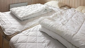 Quarto com cama, janela e paredes de madeira.
