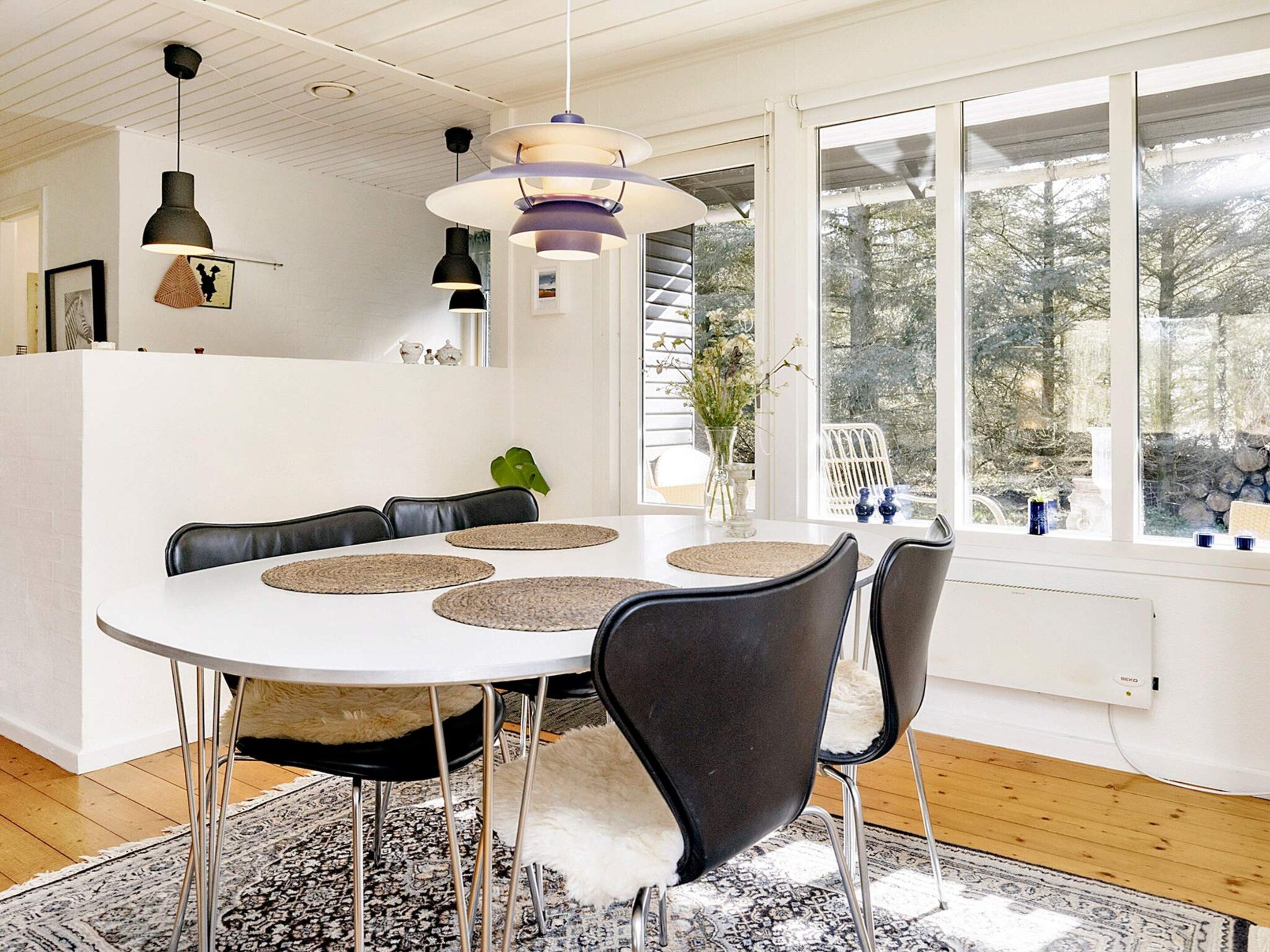 Een eetgedeelte met een ronde tafel, zwarte stoelen en een witte tafelkleed.
