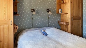 Ein Schlafzimmer mit einem Bett, einem Holzschrank und Regalen.