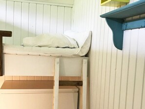 Uma cama beliche com escada, uma parede branca e uma prateleira azul.
