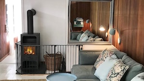 A cozy living room with a fireplace, a sofa, a round table, and a mirror. - 4 Person Holiday Home in Hornbaek (Hornbaek)