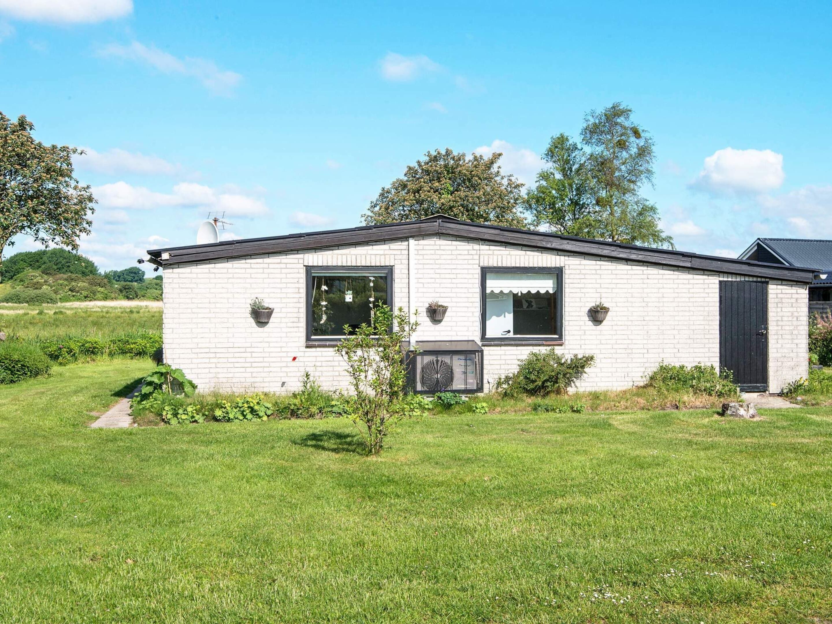 Een gelijkvloers huis met een bakstenen gevel, een kleine voortuin en een heldere lucht.