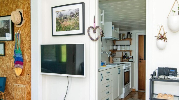 Moderni keittiö, jossa on valkoiset kaapit, sisäänrakennettu uuni ja kahvinkeitin.