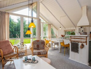 A spacious room with a dining area, wicker furniture, and a kitchen area with a hanging basket.